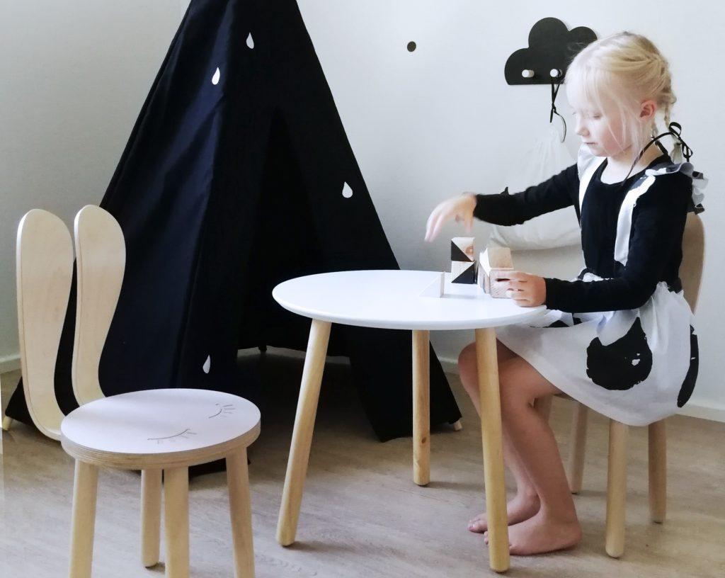 Lapsi leikkii pöydän ääressä. Emilia Åman on suojannut EK for Kids -tuotemerkin Rabbit-tuolin mallioikeudella. Kuva: Emilia Åman.