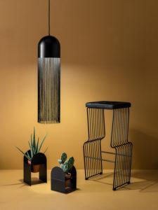 Lamppu, tuoli ja kasvitelineet ruskean seinän edessä
