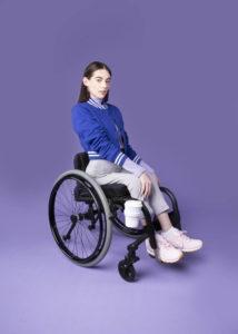 Nainen pyörätuolissa, johon on kiinnitetty muoti- ja lifestyle-brändi FFORAn mukiteline.
