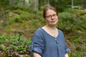 Kuvassa Taitelijat O:n syksyn 2020 vuodenaikataitelija Soile Hovila. Taustalla metsämaisema.