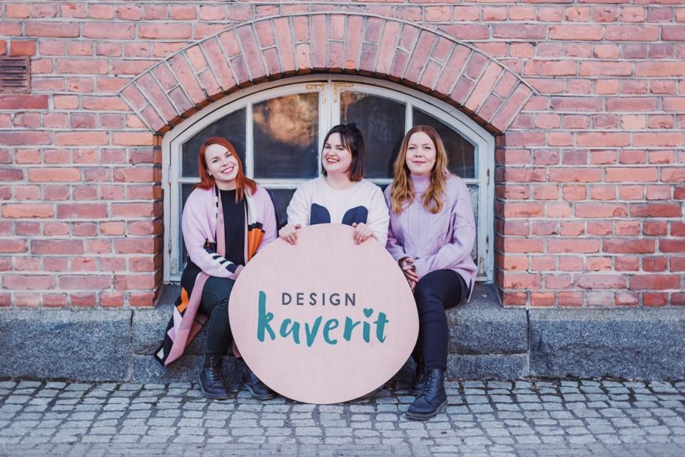 Designkaverit Essi, Ella ja Stiina ja heidän edessään iso Designkaverit-logo